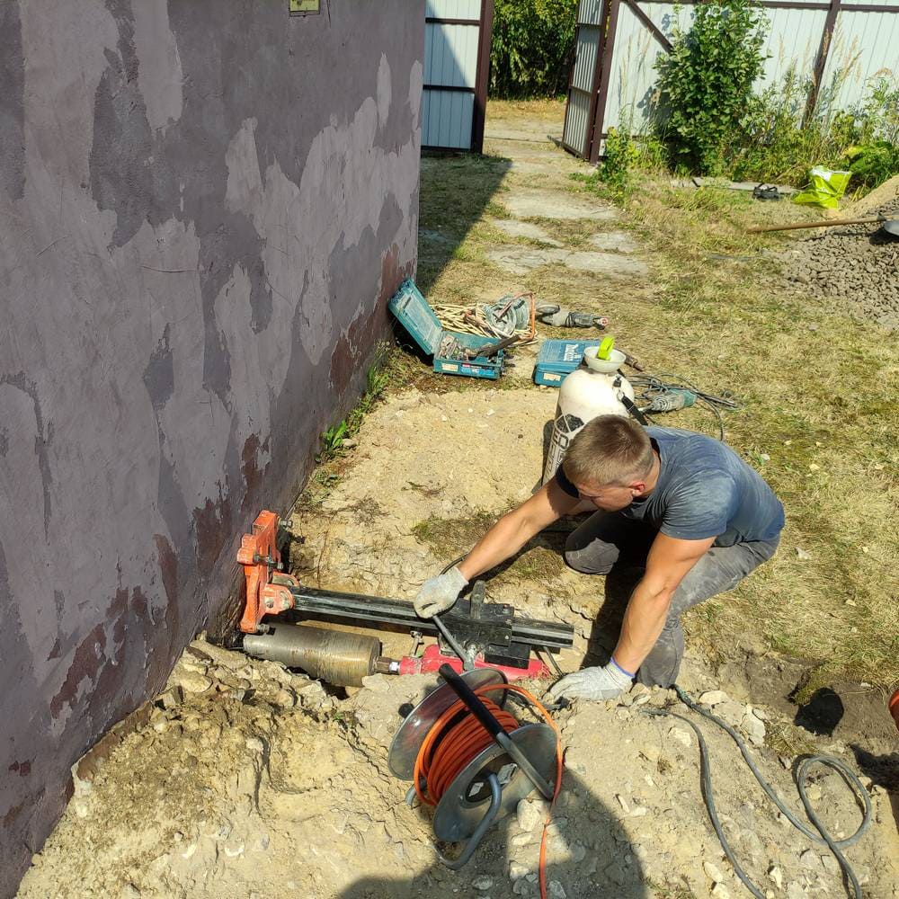 Сверление стены во время монтажа септика